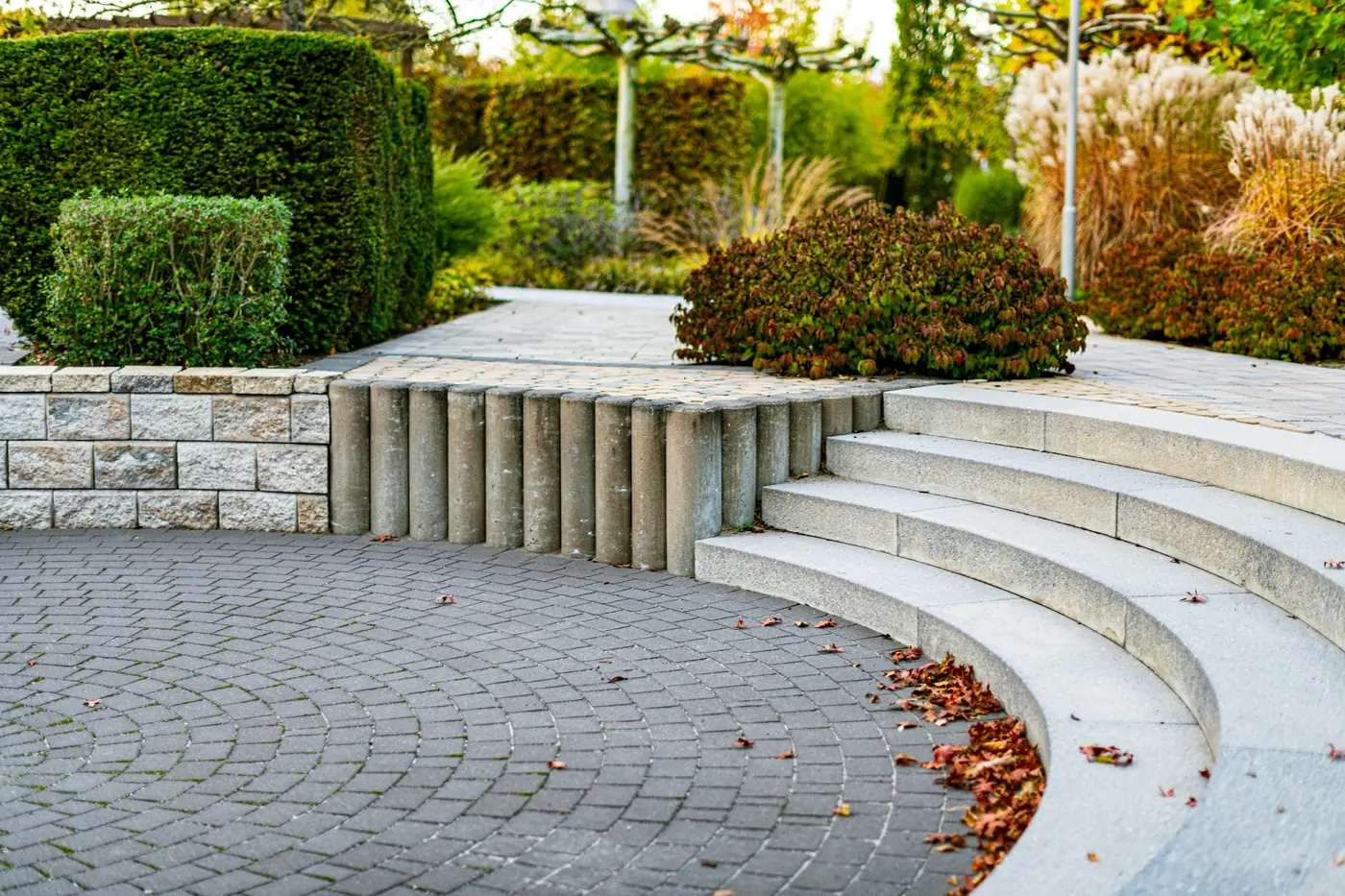 Gepflasterte Rundung mit Sitzstufen und gepflegten Hecken in einem modernen Garten