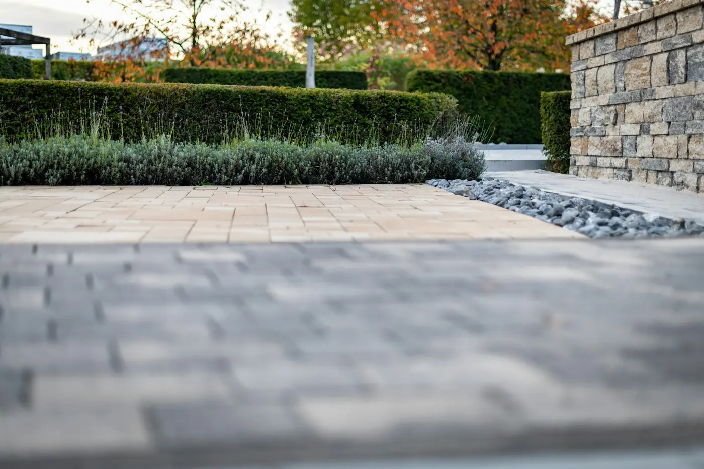 Modern gepflasterte Terrassenfläche mit Natursteinmauer und Staudenbeet